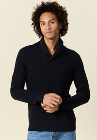 Maglione blu navy lavorato a maglia con colletto a scialle, caratterizzato da un motivo testurizzato e maniche lunghe. La vestibilità è aderente con polsini e orlo a coste.