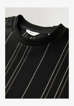 Sort ribbet kortærmet top med lodrette striber i hvid og tan. Kraven har et simpelt rundt design, med et mærke indeni.