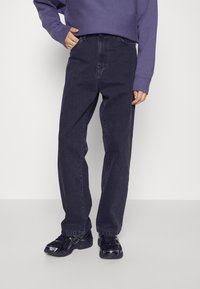 Tummansiniset farkut, joissa on rento leikkuu, korkea vyötärö ja suorat lahkeet. Yhdistetty löysään purppuraan huppariin ja mustiin lenkkikengiin.