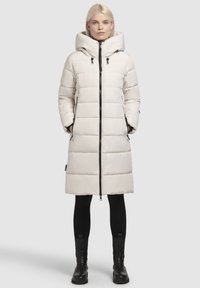 Manteau en duvet long et clair avec un col haut, une fermeture éclair frontale et des poches latérales. Présente un motif matelassé et une capuche.