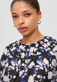 Bloemendessins blouse met tinten blauw en roze op een zwarte achtergrond, met een gerimpelde kraag en delicate afwerking.