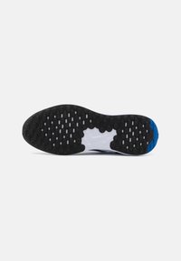 Semelle de chaussure noire en caoutchouc avec un motif de découpes circulaires. Présente une semelle intermédiaire blanche et un accent bleu sur le bout.