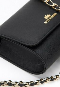 Sac bandoulière noir texturé avec une chaîne dorée et un rabat, comportant un logo embossé sur le devant.