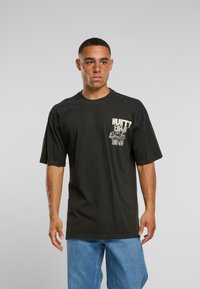 Černé bavlněné tričko s krátkým rukávem a kulatým výstřihem. Na přední straně má text a grafický design. Kombinováno s modrými džíny.