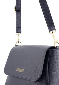 Granatowa skórzana torebka na ramię z klapą, teksturowana powierzchnia, złote akcenty oraz odpinany pasek z niebieskimi przeszyciami.