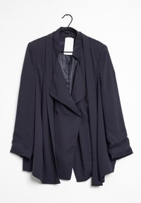 Donker marineblauwe gedrapeerde blazer met lange mouwen, hangend aan een zwarte hanger tegen een witte achtergrond.