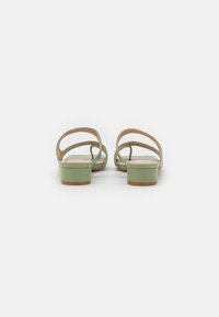 I sandali alti con tacco in pelle verniciata verde presentano un tacco a blocco basso, un retro aperto e cinturini minimalisti. Le solette testurizzate aumentano il comfort.
