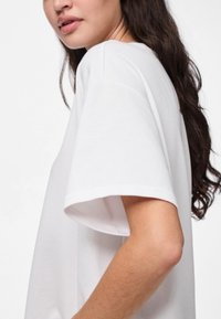 Hvit bomull t-skjorte med korte ermer, rund hals og en avslappet passform, med glatt stofftekstur og enkelt design.