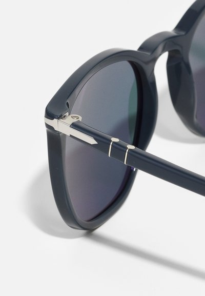 Mornarsko modre sončne očala z velikimi, zaobljenimi lečami, v kombinaciji s srebrnimi kovinskimi dodatki na okvirju in tečajih; gladka plastična tekstura.