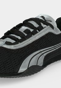 Μαύρο και ασημί αθλητικό παπούτσι Puma με υφή από δίχτυ, μαύρα κορδόνια και το λογότυπο Puma στη γλώσσα και στο πλάι του παπουτσιού.