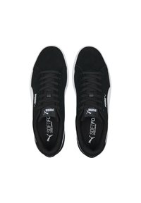 Une paire de baskets noires Puma avec des semelles blanches, des lacets noirs et des semelles intérieures "SoftFoam Optimal Comfort", vue de dessus sur un fond blanc.