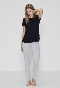 Sort bomuld t-shirt med korte ærmer og rund hals, kombineret med lysegrå, tætsiddende leggings i blødt, elastisk stof.