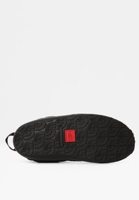 Suela de zapatilla de goma negra con un patrón de textura en la suela, acento de logo rojo y una pestaña en el talón para facilitar su uso.