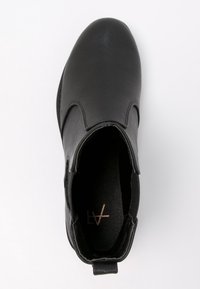Botín negro de cuero hasta el tobillo con un acabado suave, paneles laterales elásticos y puntera redondeada. Presenta una marca interior mínima y una lengüeta.