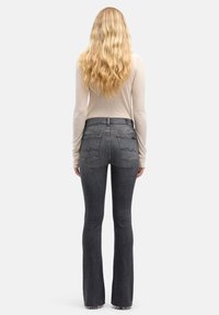 Spodnie dżinsowe z wysokim stanem i rozszerzanymi nogawkami w ciemnoszarym denimu o gładkiej fakturze, z tylnymi kieszeniami i minimalnymi detalami szwów.