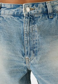 Lichtblauwe spijkerbroek van denim met een verouderde textuur, voorzien van een zilveren knoop, riemlussen en een standaard vijf-pocket ontwerp.