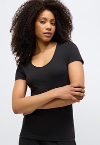 Black short-sleeve t-shirt made of soft fabric with a scoop neckline and a subtle logo accent on the hem. Smooth texture and fitted design.