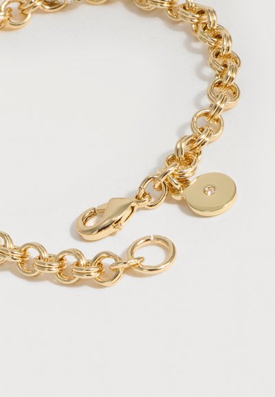 Bracelet chaîne en or avec des maillons ovales, fermoir mousqueton et petit charm rond avec une petite pierre précieuse centrée.
