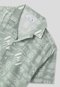 Camicia verde a maniche corte con un motivo geometrico bianco, realizzata in tessuto leggero, con colletto e un dettaglio a bottone singolo.