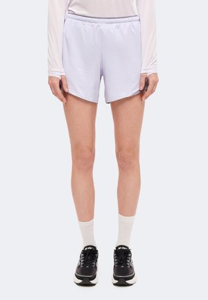 Modèle portant un short de sport lavande pâle, un haut à manches longues, des chaussettes blanches et des chaussures de course noires sur un fond uni.