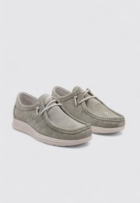 Zapatos de ante gris con punta redonda, costuras decorativas y perforaciones para transpirabilidad; cuentan con una suela flexible de color claro.
