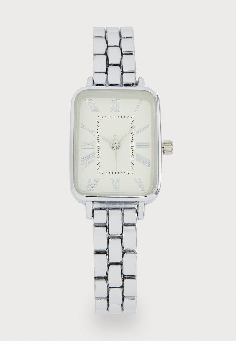 Reloj de pulsera rectangular plateado con una esfera blanca, marcadores de horas en números romanos y una pulsera de metal pulido con eslabones.