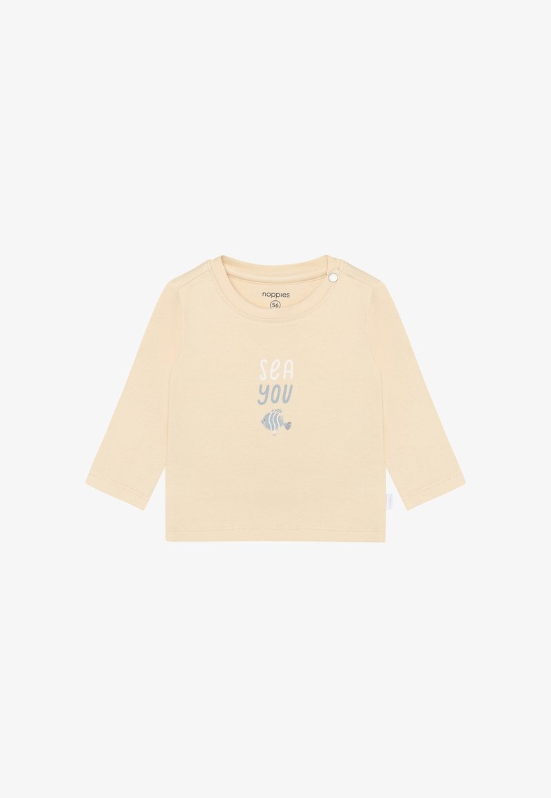 Chemise beige clair à manches longues en coton doux, avec un imprimé graphique portant le texte « SEA YOU » et un petit dessin de poisson en dessous.