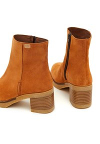 Botas de tobillo de gamuza color arena con cremallera lateral, puntera redonda y un tacón de bloque de madera texturizado. Forro interior suave.
