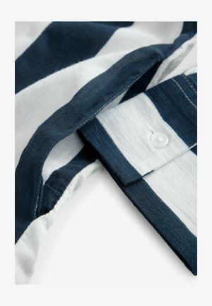 Jūronavy ir baltos juostos audinys, rodantis apykaklės ir mygtukų detales. Minkšta tekstūra su siūtu kraštu, pabrėžianti švarias linijas ir sulankstytas sluoksnius.