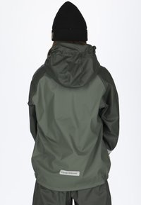 Vandtæt grøn jakke med hætte, tekstureret stof og et logo label på den nederste del af ryggen. Designet har kontrasterende mørke ærmer.