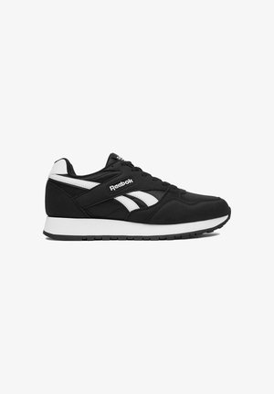 Pantof sport Reebok alb-negru cu talpă albă, logo lateral și design cu șireturi, prezentat în profil pe un fundal alb.
