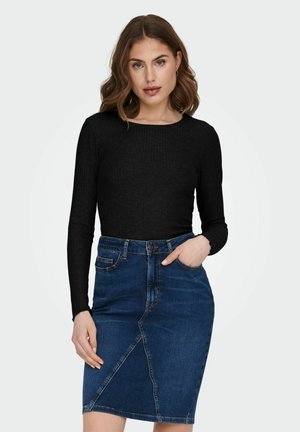 Maglietta nera a maniche lunghe a coste abbinata a una gonna a tubino in denim blu con uno spacco frontale, tasche e vita tradizionale.