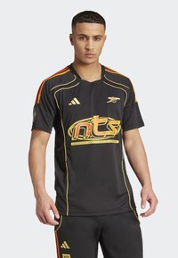 Black athletic shirt with orange and yellow accents, featuring a logo and bold text. Designed with short sleeves and a rounded neckline.