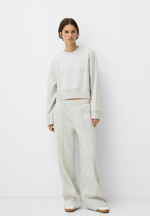 Lichtgrijze cropped sweatshirt met lange mouwen, gecombineerd met hoge, wijde sweatpants. Beide gemaakt van een zachte, textuurstof.
