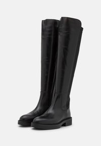 Botas de cuero negro hasta la rodilla con una textura suave, punta redonda y un tacón bajo en bloque. Presenta costuras cosidas a lo largo de los laterales.