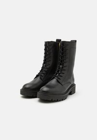 Black leather ankle boots with a sturdy, textured sole. Features include laces, a side zipper, and a reinforced toe cap.