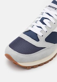 Baskets navy et gris avec un dessus en maille texturée, des accents en daim lisse et des lacets blancs. Semelle en caoutchouc pour une traction optimale.