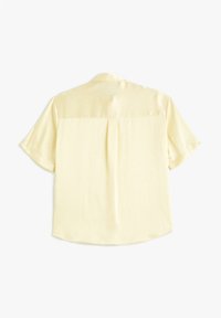 Korte mouwen, gele blouse van soepele stof; heeft een rugplooitje, een gebogen zoom en een standaard kraag voor een ontspannen pasvorm.