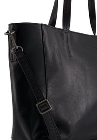 Zwarte leren tote bag met een gladde textuur, dubbele handgrepen aan de bovenkant en een afneembare schouderband met een metalen gesp detail.