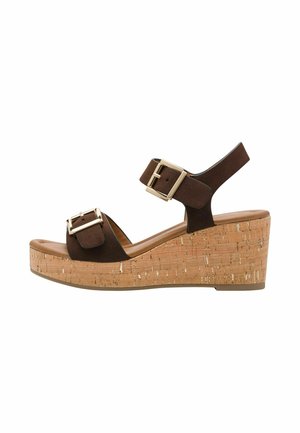 Sandales compensées en suède marron avec deux brides ajustables, boucles en métal doré, et plateforme en liège texturé. Vue de côté montrant la forme et le design.