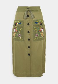 Falda verde oliva de algodón con un diseño de longitud media, que presenta patrones florales bordados en dos bolsillos frontales y un cierre de botones.