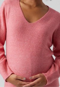 Rosa, langärmliger Pullover mit V-Ausschnitt. Hergestellt aus weichem Material, mit gerippten Bündchen und einer lockeren Passform über dem runden Bauch.