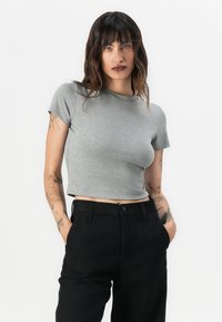 Grå kortärmad t-shirt i ett mjukt, stretchigt material med rund halsringning. Kombinerad med högmidjade svarta byxor.