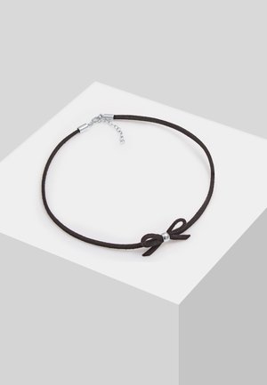 Czarny naszyjnik-obroża z cienkiego sznurka, z małym srebrnym zapięciem i kokardką ozdobioną srebrną koralikową aplikacją, prezentowany na białym tle.