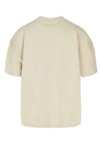 Krémové oversized tričko s krátkým rukávem a kulatým výstřihem, s hladkým povrchem a bez viditelných vzorů či akcentů na zadní straně.