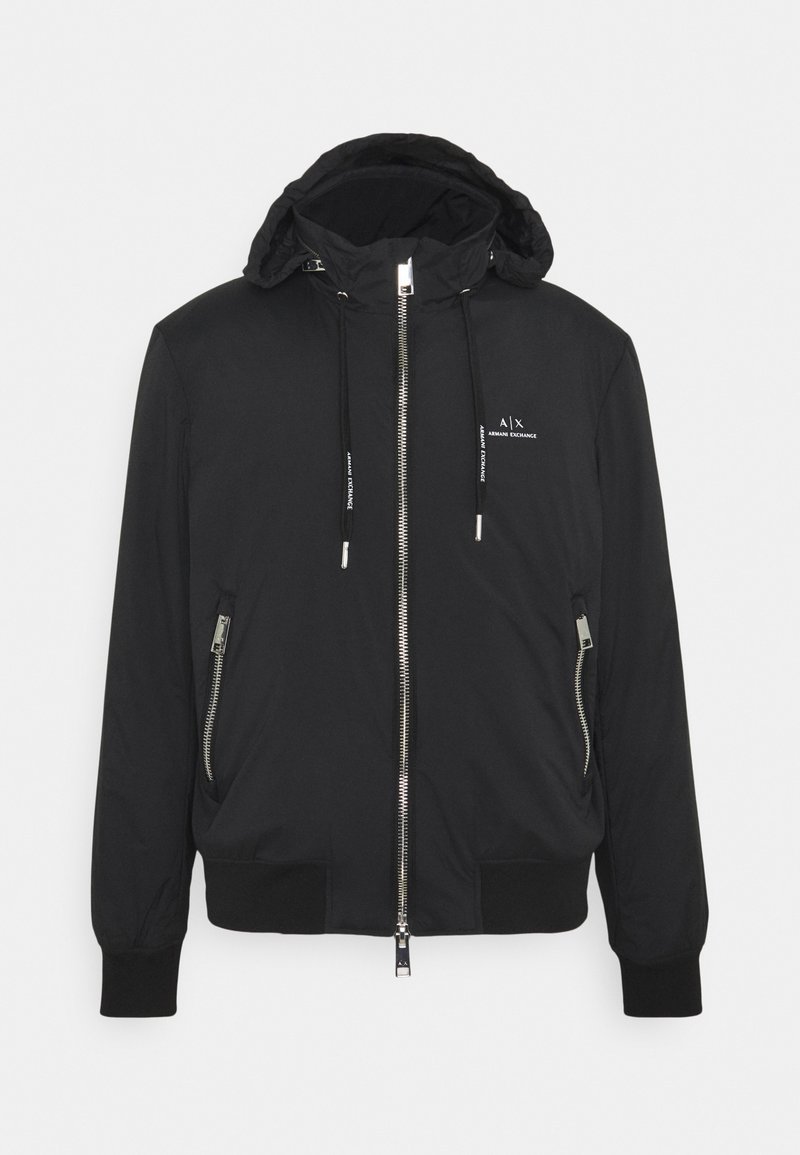 Musta bomber-takki hupulla, edessä vetoketju, sivuilla vetoketjulliset taskut ja resorit. Sisältää logotiedot rinnassa ja narut.