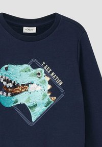 Marineblauer Sweatshirt mit einem T-Rex-Kopf aus Pailletten, in verschiedenen Blautönen und einem goldenen Akzent auf den Zähnen. Der Text "T-REX NATION" ist ebenfalls enthalten.