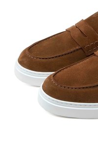 Braune Wildleder-Slipper mit einer weißen Gummisohle. Sie verfügen über eine runde Zehenpartie, gestickte Details und einen Riemen über dem oberen Teil.