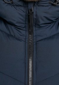 Marineblauwe donsjack met een ritssluiting over de volle lengte, verstelbare capuchon met trekkoorden, doorgestikte textuur en versterkte naden voor duurzaamheid.