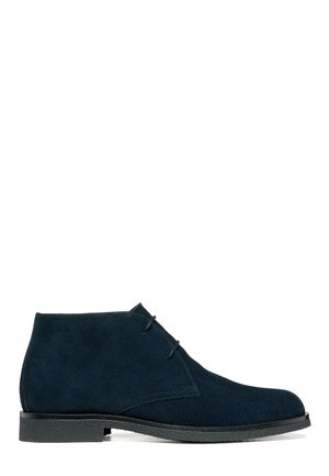 Bottes pour homme en daim bleu foncé avec semelle noire et fermeture à lacets à deux œillets, présentées sur fond blanc.